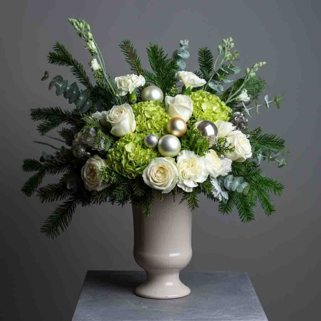 This centerpiece features a luxurious array of white roses, green hydrangea, white carnations mixed wintergreens and festive accents.